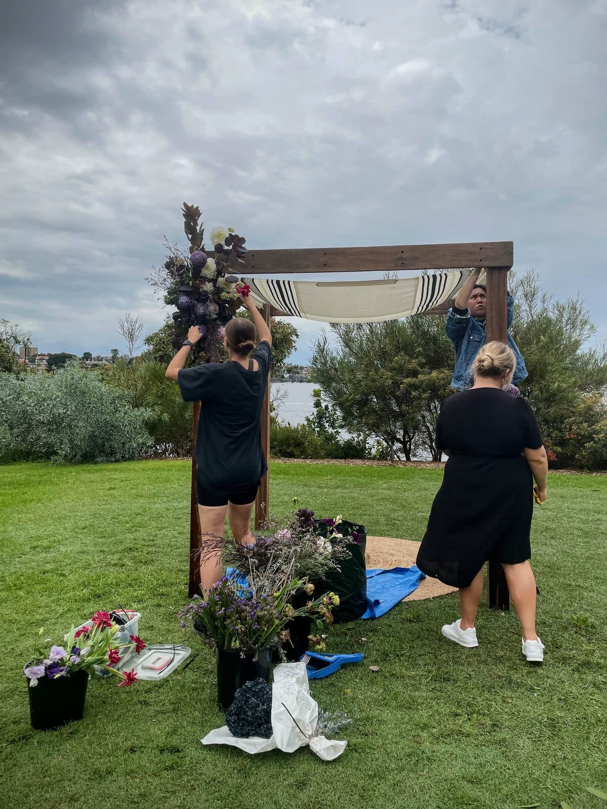 Florists installing a floral arbour together at an outdoor wedding setup